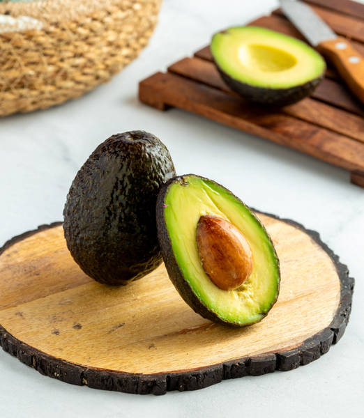 a half cut avocado infront of an uncut one
